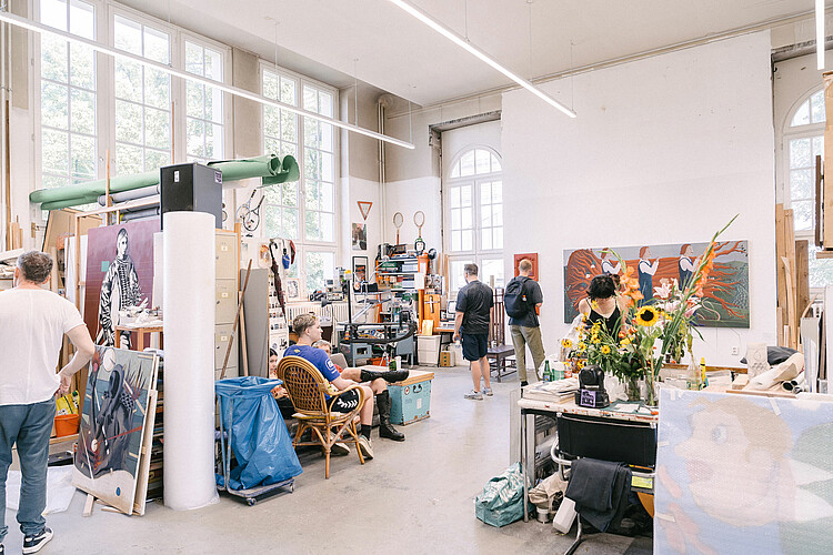 Das Bild zeigt ein Atelier der Hardenbergstraße mit farbigen Bildern und Menschen im Raum