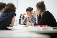 Fünf Personen in einer Beratungsrunde an einem Tisch.